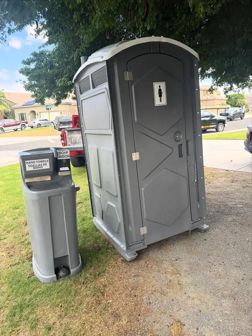 Standard porta potty with a hand wash station on grass, the kind of setup we deliver in Starke